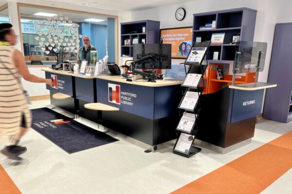The main circulation counter features custom signage and colors which connect with the Library branding and interiors.