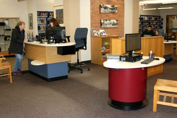 YAKETY YAK 307 Island Counter brings a new dimension to customer service, while YAKETY YAK 102 Oval Pod provides a new and inviting self-help desk for patrons, at Woodstock Public Library, IL.