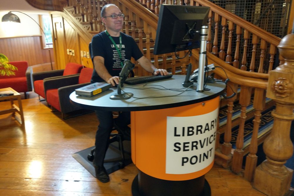 A modern Yakety Yak Oval 101 pod welcome station deployed in a grand old university library.